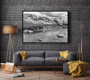 Black and white coastal landscape with fractured granite and still water