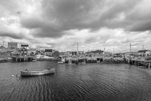Small rowboat floating before wooden wharves in Peggy’s Cove harbour
