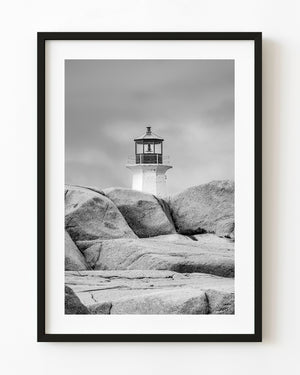 Peggy’s Cove lighthouse rising beyond rounded granite rocks, black and white