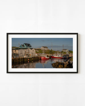 Red fishing boats in Peggys Cove harbor at sunrise