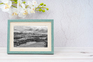 Monochrome shoreline detail with rock cracks, seaweed and still pools