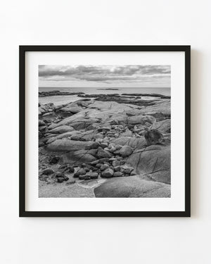 Peggy’s Cove rocky shore and Atlantic Ocean beneath clouds, black and white