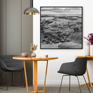 Small boulders gathered between smooth rock surfaces on the coast