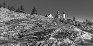 Maine lighthouse and keeper’s buildings beyond folded shoreline rock