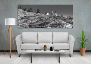 Wide monochrome view of layered coastal rock beneath Pemaquid Point light
