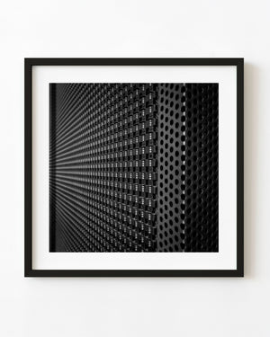 Black and white close-up of repeating perforations and fasteners on a metal façade