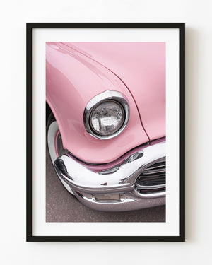 Chrome-ringed headlight and pink fender of a 1956 Oldsmobile