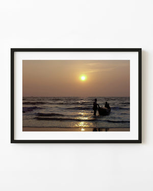 Fishermen beside a small boat at Pollenthai Beach beneath a golden sunset
