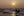 Silhouetted fishermen in shallow surf with sunlight reflected across the sea
