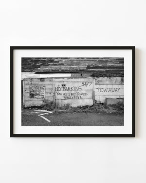 No Parking warnings on a weathered Portland fish market wall in black and white