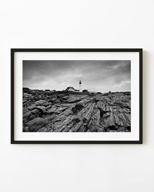 Portland Head Light above rugged coastal rocks in black and white