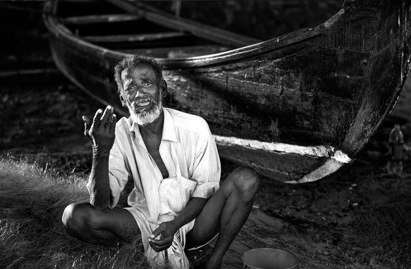 Fisherman mending nets by boat