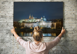 Night view of Prague with golden and blue lights reflected on the river