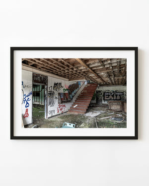 Abandoned Pruce’s Motor Inn lobby with red stairs and graffiti-covered walls