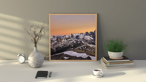 Warm evening light behind rugged peaks and alpine snowfields