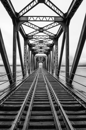Steel truss train bridge crossing over frozen river in Canada