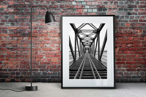 Monochrome railway crossing framed by steel supports
