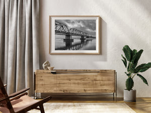 Quebec steel railway bridge reflected in dark water beneath a cloudy sky
