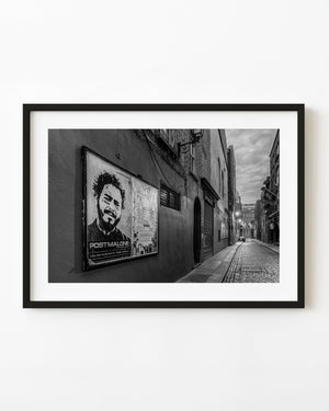 Quiet Dublin cobblestone street at dawn with concert posters and glowing lamps