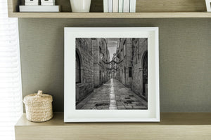 Dubrovnik alleyway receding between historic stone buildings beneath a cloudy sky