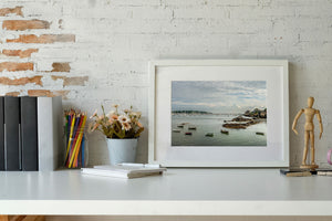 Colour coastal photograph of small boats near dark shoreline rocks