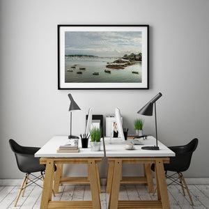 Rows of moored sailboats beyond a quiet anchorage with scattered dinghies