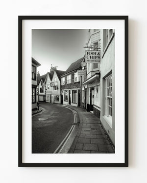 Quiet curved street in Rye England with hanging fish and chips signs