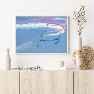 Curving smoke ribbons surrounding five red aerobatic aircraft