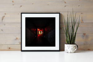 Dark corridor leading toward a brightly lit doorway beneath an Art sign