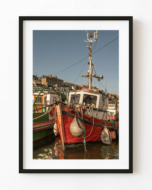 Weathered red fishing boat moored beside a green boat in Cobh harbour