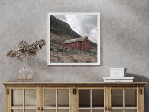 Small Norwegian boathouse at the foot of a dark mountain slope