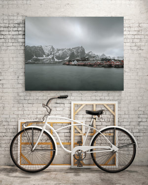Muted coastal landscape with red cabins and dramatic winter mountains
