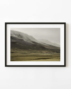 Iceland rural farmhouses beneath fog covered mountain landscape