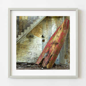 Vivid red rowboat leaning against a rustic wall