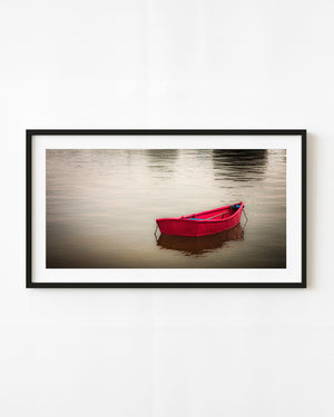Red rowboat floating on calm water in Martha’s Vineyard harbour