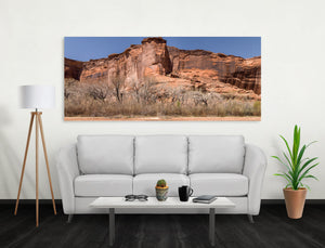 Wide colour photograph of red sandstone cliffs with weathered dark streaks
