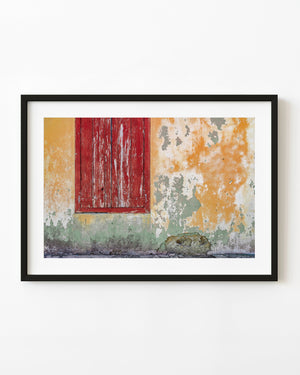 Weathered red wooden shutter on a peeling yellow and green wall in the Bahamas
