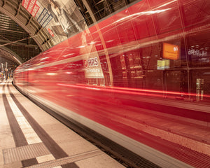 Moving red train sweeping past Dresden railway station platform
