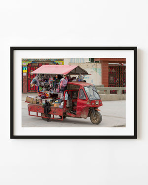 Red three-wheeled vendor truck loaded with goods on a street in China