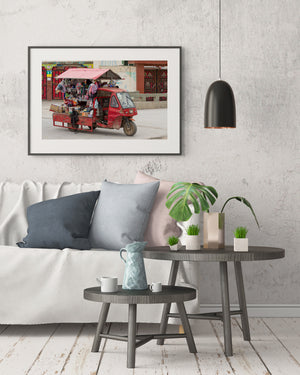 Colourful goods displayed on a worn red three-wheeled truck