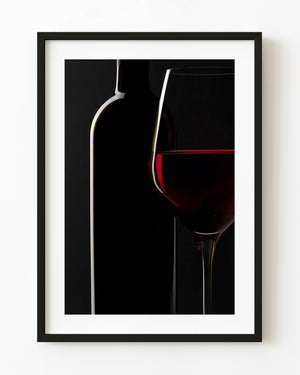 Red wine glass and bottle against a black background