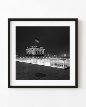 Reichstag rooftop at night with an illuminated stone tower and German flag in black and white