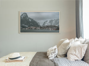 Calm bay and small illuminated houses beneath snow-dusted peaks