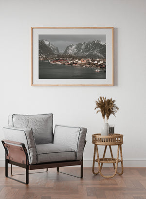 Small boats and waterfront cabins framed by towering snowy Norwegian peaks