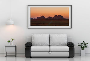Sandstone buttes rising above a quiet road in Monument Valley