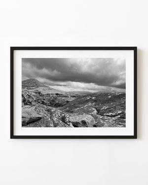 Rocky hillside near Inch Beach in Ireland beneath dark clouds in black and white