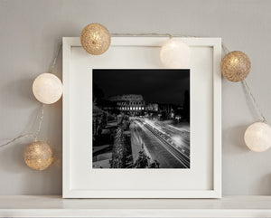 Colosseum at night viewed above a busy cobbled street