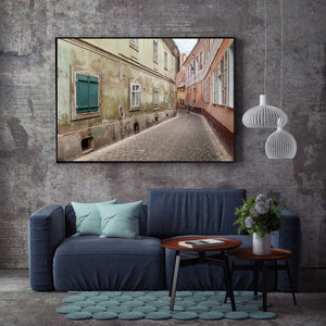 Weathered historic buildings enclosing a winding stone-paved lane