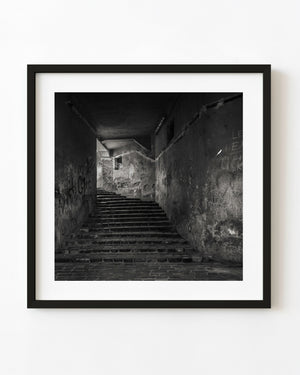 Romanian stone stairway climbing through deep shadow between worn walls
