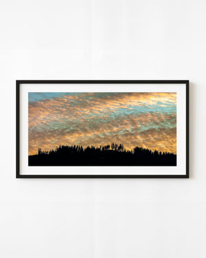 Golden sunset clouds above a silhouetted Romanian forest ridge